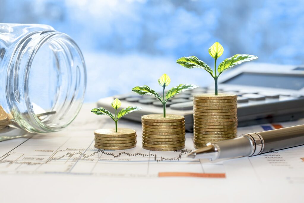 tiny trees coming out of stacks of coins with a calculator in the background - trees are edited into the image