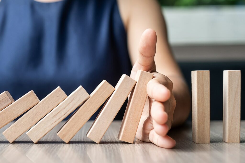 woman with blue shirt stopping small blocks from falling against more blocks