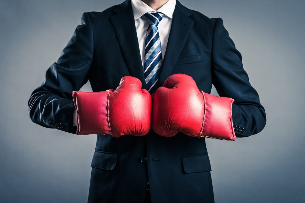 man in a business suit wearing red boxing gloves
